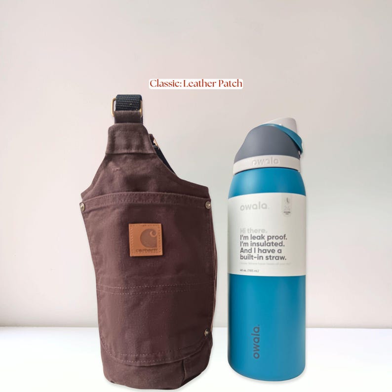 Brown canvas water bottle holder with original leather patch of the Carhartt logo on the back pocket, displayed next to a tall insulated bottle.
