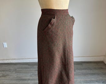 May include: A vintage, knee-length skirt in a textured brown and red speckled fabric. The skirt features a high waist, two front pockets, and a tailored fit. The garment is displayed on a mannequin.