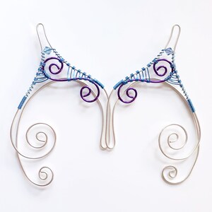 May include: A pair of silver wire ear cuffs with purple and blue wire accents and small blue beads.
