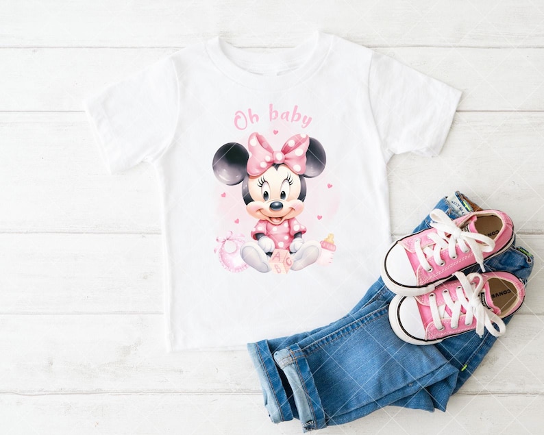 K&ouml;nnte beinhalten: Wei&szlig;es T-Shirt mit Minnie Mouse-Grafik und dem Text "Oh baby". Das Design umfasst eine rosa Schleife, ein Kleid und Details. Dazu blaue Jeans und rosa Turnschuhe.