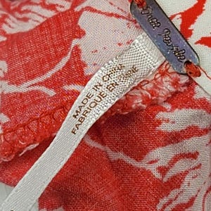 May include: Close-up of a red and white floral patterned fabric. The fabric has a tag that says "Free People" and a label that says "MADE IN CHINA FABRIQUE EN CHINE". The number "8" is also visible.