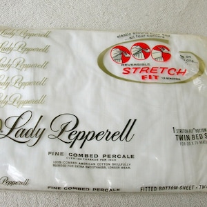 May include: A white package with a gold logo for Lady Pepperell fine combed percale twin bed size stretch-fit bottom sheet. The package has the text "REVERSIBLE STRETCH FIT 1/2 STRONGER" and instructions for using the sheet.