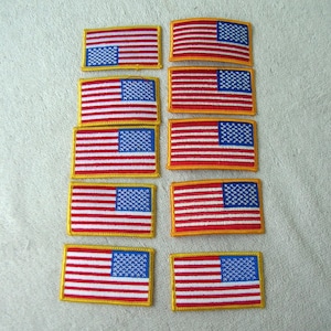 May include: Ten embroidered American flag patches with a gold border. The flags are red, white, and blue with a white field of stars.