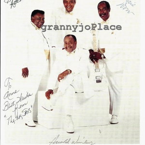 Puede incluir: Una fotografía en blanco y negro de cuatro hombres con trajes blancos, sonriendo y sosteniendo una guitarra. Los hombres están identificados como "The Ink Spots" y la foto está firmada por cada uno de los hombres. El texto "To Anne Best Wishes from "The Ink Spots" está escrito en tinta negra en la esquina inferior izquierda de la foto.