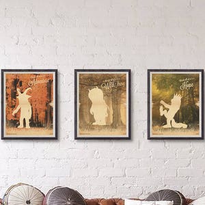 May include: Three framed prints with a white silhouette of a creature from the book Where the Wild Things Are. The prints are hung on a white brick wall above a brown leather sofa with pillows. The prints are titled "Adventure", "Wild Thing", and "Hope".