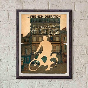 Può includere: Poster vintage incorniciato con il testo "THE FRENCH DISPATCH" e "All Grand Beauties Withhold Their Deepest Secrets." Il poster presenta la silhouette di una persona in bicicletta davanti a un edificio. Il poster è in una cornice marrone scuro.
