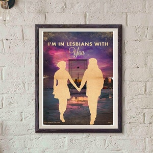 Puede incluir: Un p&oacute;ster enmarcado con un fondo de puesta de sol morado y rosa. El p&oacute;ster presenta dos siluetas de personas que se toman de la mano frente a una puerta con el texto "I'm in lesbians with you".