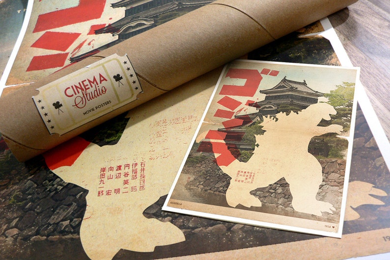 May include: A vintage-style poster featuring a silhouette of Godzilla standing in front of a Japanese castle. The poster is printed on aged paper with a red and white color scheme. The text on the poster reads "Godzilla" in Japanese characters.
