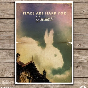 Puede incluir: Un p&oacute;ster de estilo vintage con un fondo descolorido y texturado. El p&oacute;ster presenta una nube blanca con forma de conejo en un cielo azul. El texto "TIMES ARE HARD FOR DREAMERS." est&aacute; impreso en una fuente dorada en la parte superior del p&oacute;ster.