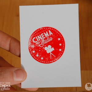 May include: A white card with a red circle containing the text "CINEMA Studio" and a white silhouette of a film camera.