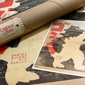 Puede incluir: Un p&oacute;ster de estilo vintage con una silueta de Godzilla de pie frente a un castillo japon&eacute;s. El p&oacute;ster est&aacute; impreso en papel envejecido con un esquema de color rojo y blanco. El texto "ゴジラ" est&aacute; impreso en letras rojas grandes en la parte superior del p&oacute;ster.