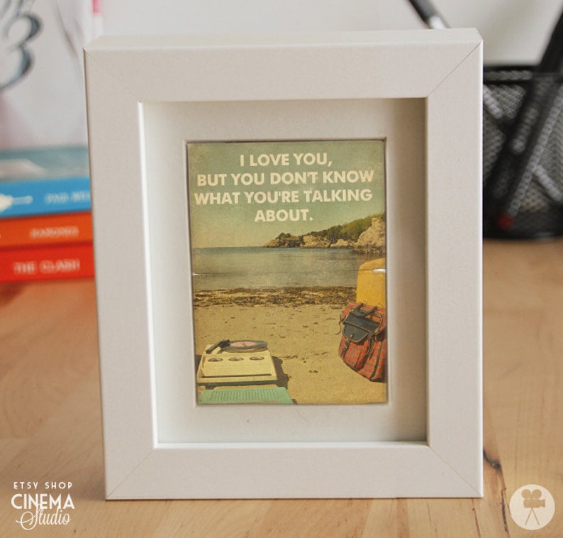 May include: A white framed print with a vintage aesthetic featuring a beach scene with a record player and a quote that reads "I love you, but you don't know what you're talking about."