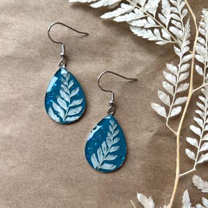 Boucles d’oreilles fougères blanches fond vert-bleu