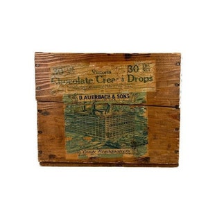 May include: A wooden crate with a label that reads "Victoria Chocolate Cream Drops 30 lbs net D. Auerbach & Sons Candy Headquarters".