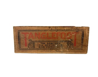 Könnte beinhalten: Eine Holzkiste mit den Worten "Tanglefoot The Sanitary Fly Destroyer Non-Poisonous" auf der Vorderseite.