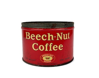 Może przedstawiać: Winylowa, czerwona puszka po kawie Beech-Nut ze złotymi literami. Puszka ma ciemną obwódkę i logo marki Beech-Nut. Widoczne są również napisy "NET WEIGHT" i "ONE POUND".