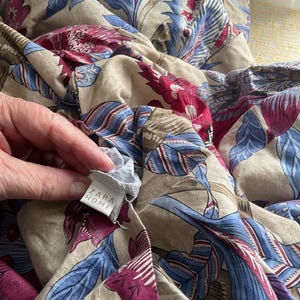 Puede incluir: Tela beige con estampado floral en azul y burdeos. El dise&ntilde;o presenta un estampado bot&aacute;nico a gran escala. La etiqueta dice "ZARA HOME".