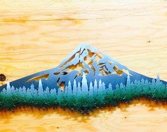 Puede incluir: Arte de pared de metal que representa una cordillera con un degradado azul y verde. La cordillera está recortada sobre un fondo de madera.