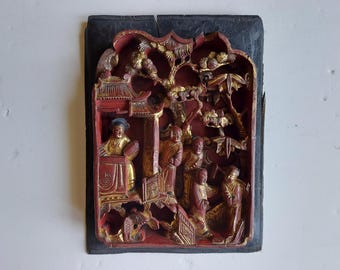 Placa de pared antigua de madera tallada con motivos chinos, en rojo y dorado.