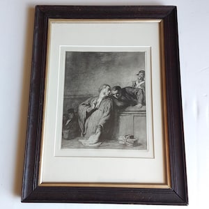May include: A framed black and white etching depicting a courtroom scene with figures in robes. The central figure stands while another leans over a wooden partition to whisper. A stack of documents sits on the ledge. The frame is dark brown wood.