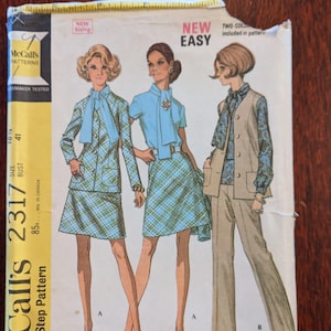 May include: Vintage McCall's sewing pattern 2317 featuring illustrations of women's coordinates. The pattern includes a skirt suit, a blouse and skirt set, and a pantsuit. The package is yellow and white with the text "NEW EASY".