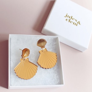 May include: Gold mirrored seashell earrings in a white gift box with the text "Jules & Clem" on the box lid.