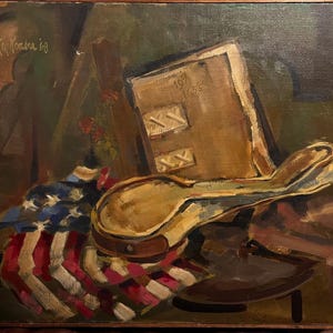 May include: An oil painting featuring a still life composition. The artwork depicts a book, a hat, and a folded American flag. The color palette includes shades of brown, red, white, and blue. The painting is signed "Kay Konora '18".