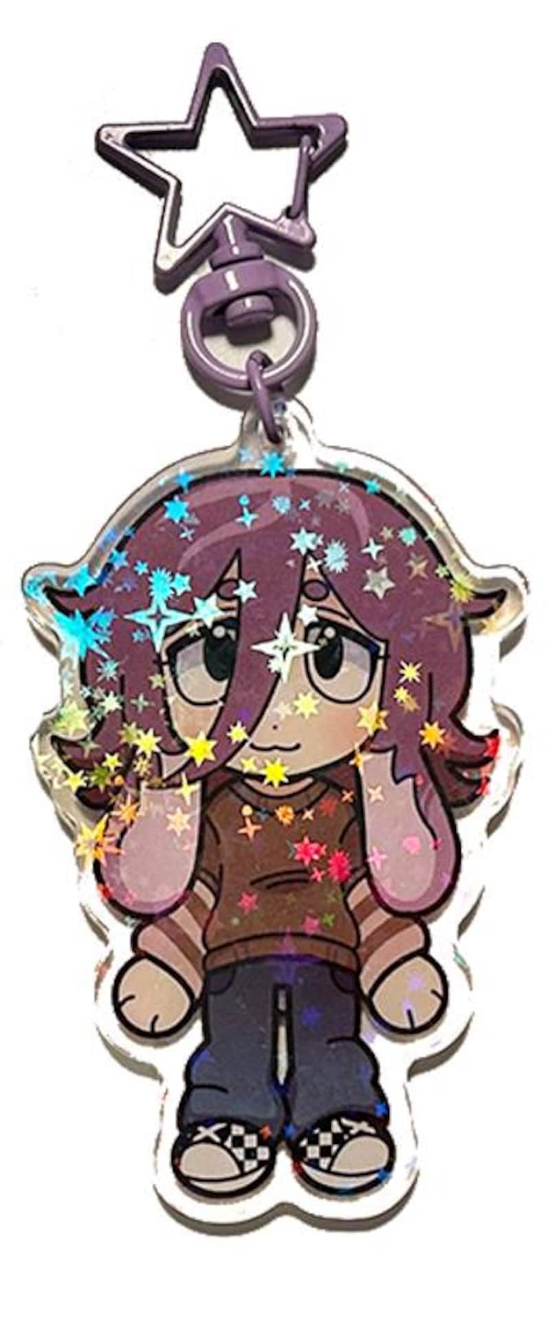 May include: A clear acrylic charm featuring a cartoon character with purple hair and a brown shirt. The charm has a star-shaped clasp and is decorated with holographic glitter and star accents. The character is wearing blue jeans and checkered shoes.