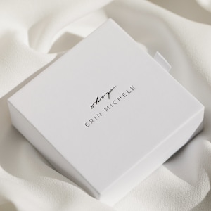 以下が含まれることがあります： 黒い文字で「shop erin michele」と印刷された白い正方形の箱
