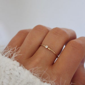 May include: A delicate gold ring with a single small diamond set in the centre.