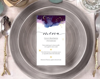 Op de afbeelding: Een menukaart met een donkerblauwe en paarse aquarel achtergrond met gouden sterren en een halve maan. De tekst op de kaart luidt "menu", "Celente's Baby Shower", "1 november 2020", "Twee gebakken geitenkaas soufflés met appel- en walnootsalade", "Pan-gebakken kip in champignonsaus op groentetaartjes met wilde salade", "Boerset Panna cotta, appel en amandelcake".