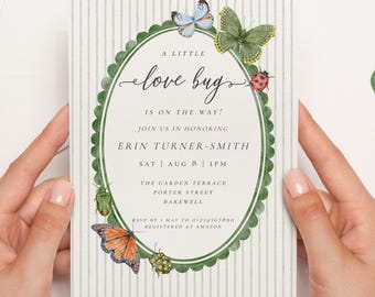 Puede incluir: Una invitación a un baby shower con un marco ovalado festoneado verde, adornado con mariposas de acuarela y una mariquita. El texto dice "A Little Love Bug Is On The Way!" e incluye los detalles del evento. El fondo tiene rayas verticales.