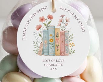 May include: A white round favor tag with pink floral illustrations and a stack of colorful books. The text on the tag reads "Thank you for being part of my story. Lots of love Charlotte xxx".