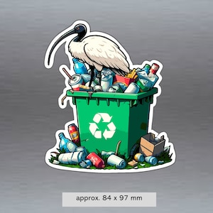 May include: A white ibis bird perched on top of a green recycling bin filled with various items, including cans, bottles, and food packaging. The bin has a recycling symbol on the front. The image is approximately 84 x 97 mm.