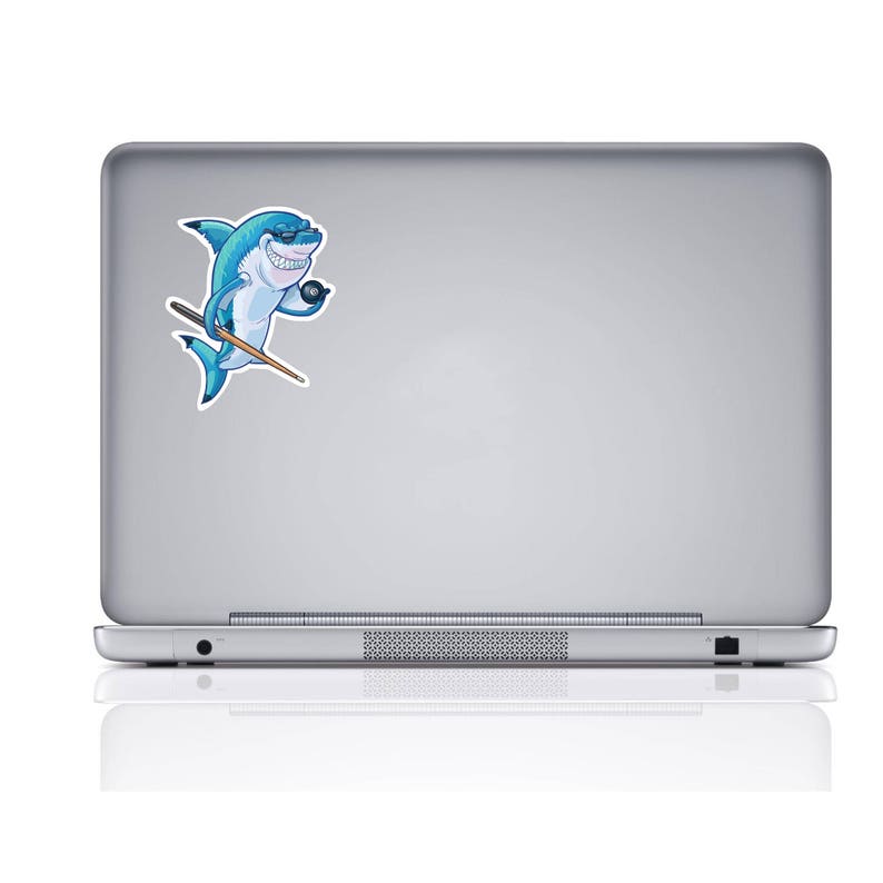 May include: A blue shark cartoon character holding a pool cue and a black eight ball. The shark is wearing sunglasses and has a toothy grin. The cartoon is on a silver laptop.