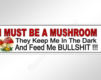Op de afbeelding: Witte bumper sticker met rode tekst die "I MUST BE A MUSHROOM They Keep Me In The Dark And Feed Me BULLSHIT!!!" luidt.  Aan de linkerkant van de sticker staat een cartoonafbeelding van twee rode en witte paddenstoelen met groene stelen.