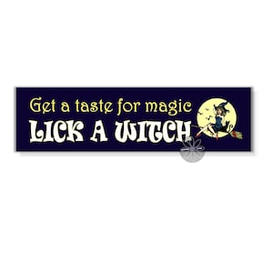May include: A dark blue sign with the text "Get a taste for magic Lick a Witch" in yellow and white lettering. A witch with a black cat flies on a broomstick in front of a full moon.