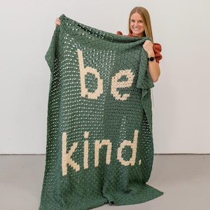 May include: A green crocheted blanket with the words "be kind" in cream colored yarn.