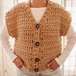 May include: A crocheted vest with a button closure. The vest is a light brown color and has a simple, classic design.