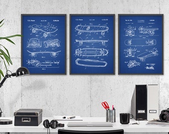 May include: Three framed blueprint style prints of skateboard designs on a white wall above a white desk with a black lamp, a black box, a laptop, a cup, a camera, and two binders.
