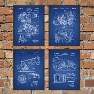 May include: Four framed construction equipment patent prints. Each print features detailed blueprints of different machines, including a bulldozer, backhoe, crane, and road roller. The blueprints are white on a blue grid background.