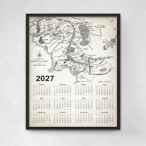 May include: A framed wall calendar for the year 2027 featuring a detailed black and white map of Middle-earth. The top section displays the cartographic illustration with place names, while the bottom section lists the twelve months of the year.