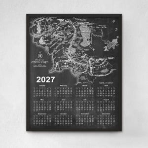 May include: A framed wall calendar for the year 2027 featuring a detailed black and white map of Middle-earth. The top section displays the geographical map with labeled regions, while the bottom section lists the twelve months with dates.