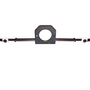 May include: A black metal device with a central circular opening and two end pieces with circular openings. The device has a horizontal bar connecting the pieces, with white components along the bar. The device is designed for mounting or support.
