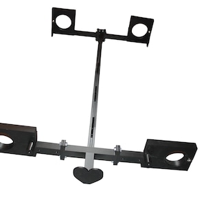 May include: A black metal frame structure featuring a long central bar connected to two horizontal crossbars. Each crossbar holds two black rectangular blocks with circular cutouts. A small black heart-shaped piece is attached to the central bar.