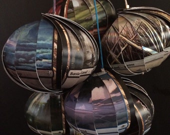 Könnte beinhalten: Eine Sammlung von sechs kugelförmigen Ornamenten aus Magic: The Gathering-Karten. Jedes Ornament besteht aus mehreren Karten, die übereinander gelegt wurden, um eine Kugel zu bilden. Die Karten zeigen verschiedene Landschaften und den Text "Basic Land" und "Island".