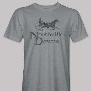 May include: A gray t-shirt with a vintage-style graphic of a horse-drawn carriage and the text "Northville Downs".