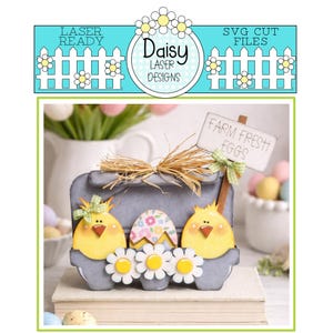 Peut inclure: Un carton à œufs de Pâques en bois gris décoré de poussins jaunes, de marguerites et d'un œuf floral. Le carton porte une pancarte indiquant "Farm Fresh Eggs". La bannière supérieure indique "Laser Ready" et "SVG Cut Files".