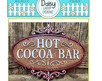 May include: A wooden sign with the words "HOT COCOA BAR" in white, light blue, and brown. The sign has a red border and decorative scrollwork. The background is a wooden surface.