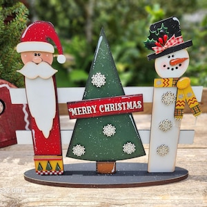 This laser cut file is a Christmas Trio Picket fence featuring a Santa, Christmas Tree and a Snowman. Either a Shelf or porch sitter.
